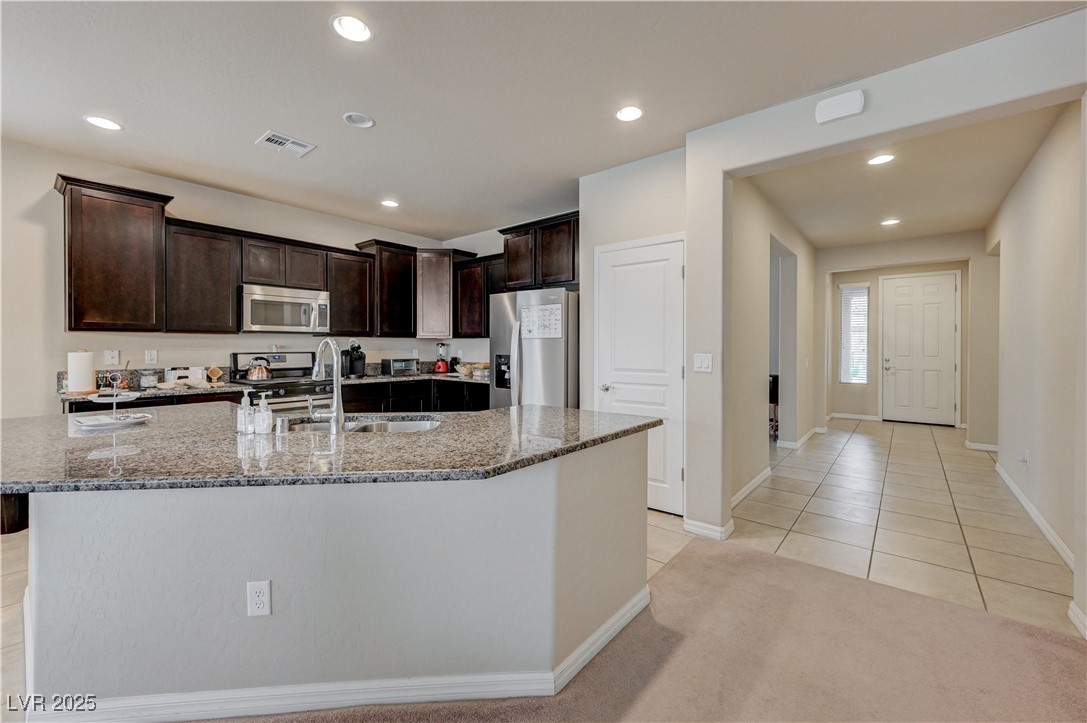6970 Motley Road Las Vegas, NV 89178 - Photo 8 of 52 Kitchen with island, espresso cabinets, stainless steel appliances, recessed lighting, granite countertops, pantry, ceramic tile flooring