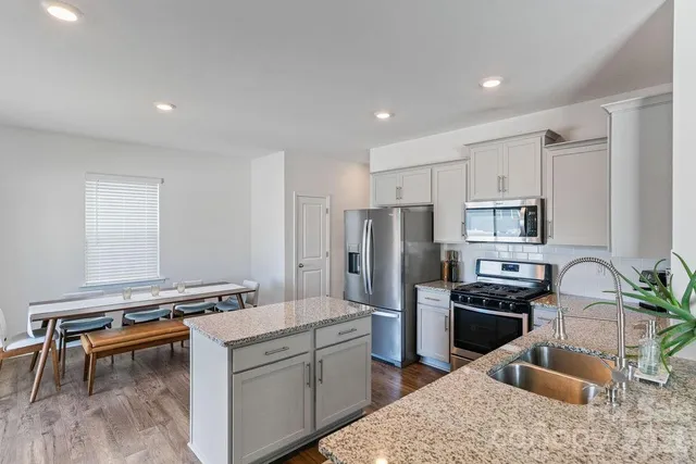 a kitchen with stainless steel appliances kitchen island granite countertop a refrigerator stove and sink