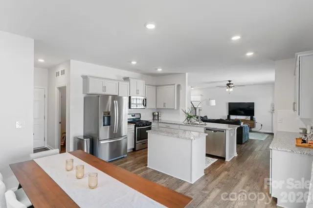 a kitchen with stainless steel appliances kitchen island granite countertop a refrigerator and a stove top oven