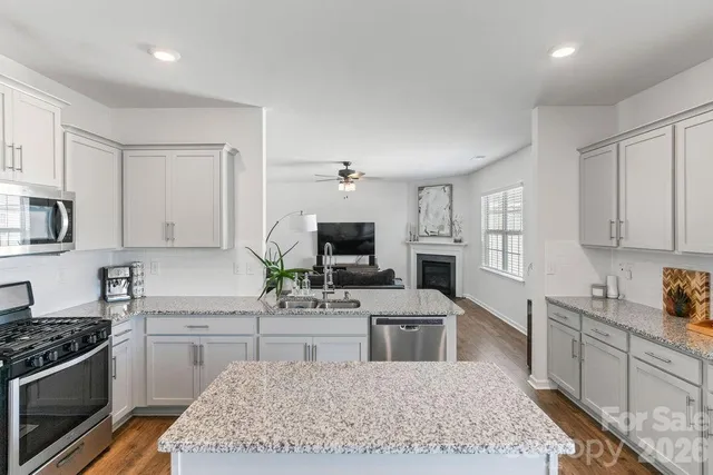 a kitchen with stainless steel appliances granite countertop a stove top oven a sink a counter space and cabinets