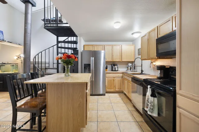 a kitchen with granite countertop a refrigerator a stove top oven a dining table and chairs with wooden floor