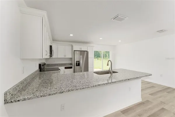 a kitchen with stainless steel appliances granite countertop a sink a refrigerator and a granite counter tops