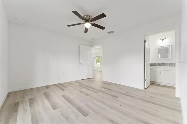 an empty room with wooden floor and a ceiling fan