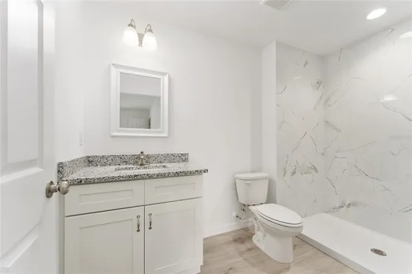 a bathroom with a granite countertop toilet sink and mirror