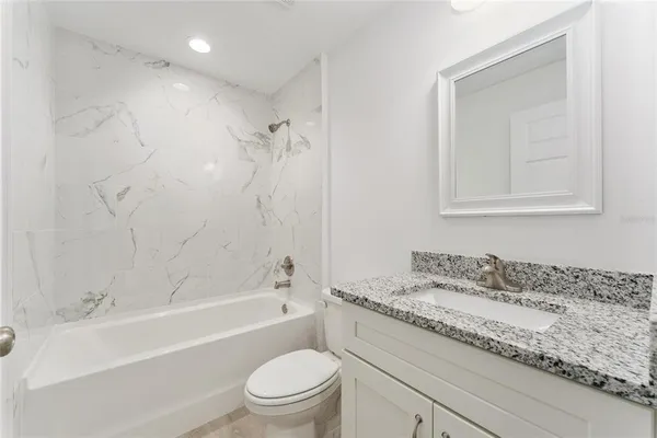 a bathroom with a granite countertop sink a toilet and bathtub