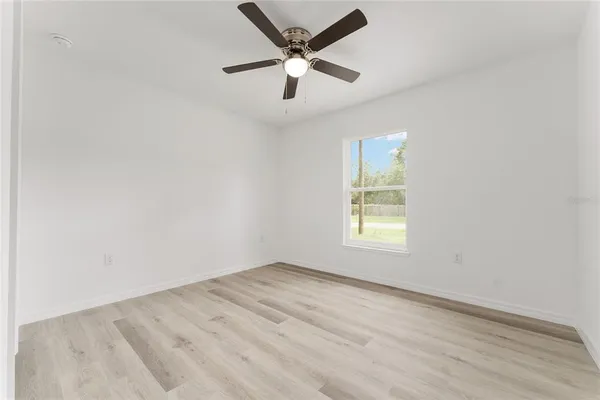 an empty room with a window and a fan