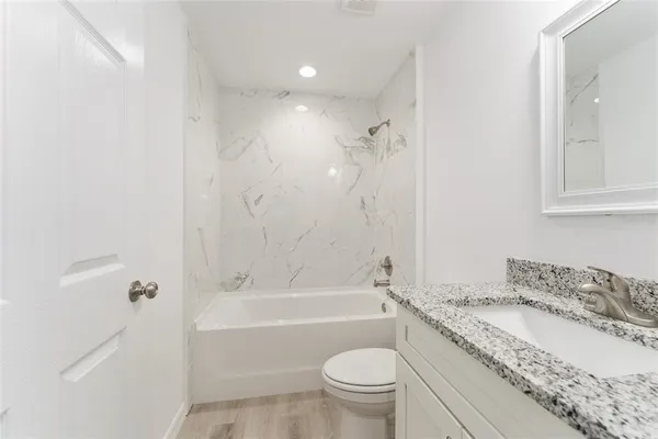 a bathroom with a granite countertop sink a toilet and bathtub