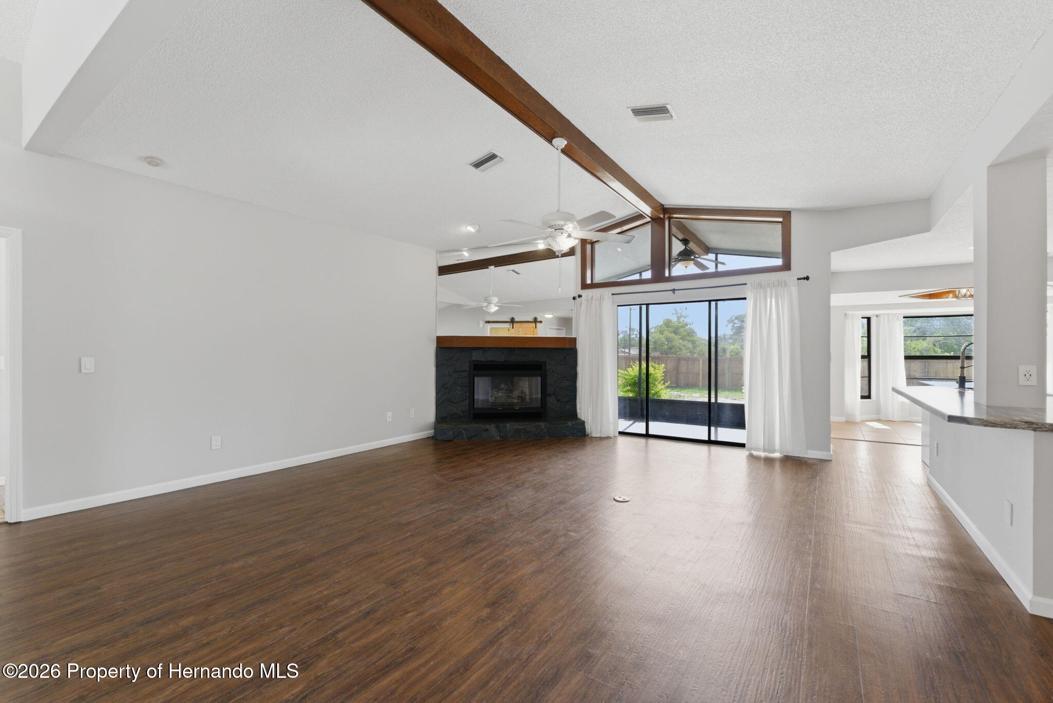 4966 Keysville Avenue Spring Hill, FL 34608 - Photo 13 of 50 a view of an empty room with wooden floor fireplace and a window