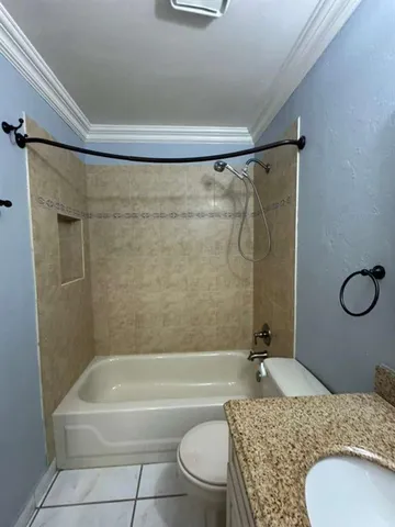 a bathroom with a granite countertop bathtub shower sink vanity and toilet