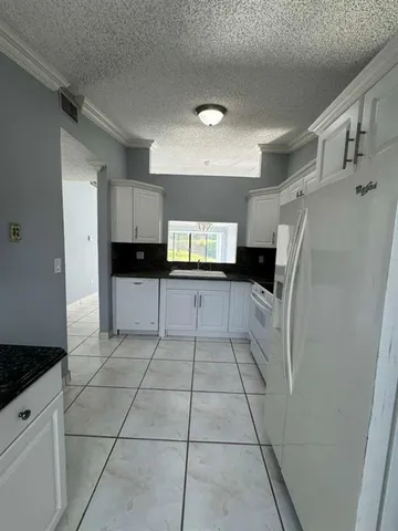 a kitchen with granite countertop a refrigerator and a sink