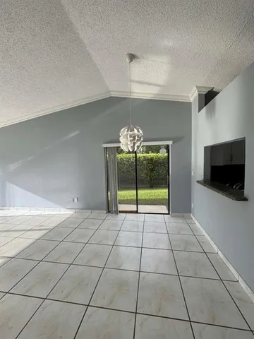 a view of an empty room with window and chandelier