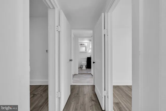a view of a hallway with wooden floor and a bathroom