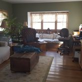 a living room with furniture large window and wooden floor