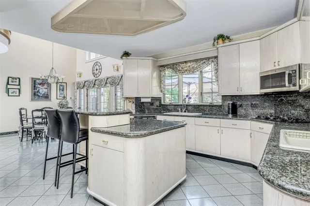 a kitchen with stainless steel appliances granite countertop a stove a sink and a microwave