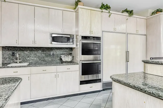 a kitchen with granite countertop white cabinets and stainless steel appliances