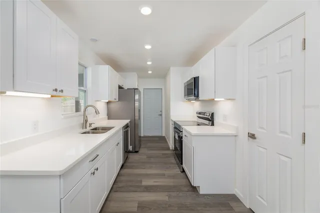 a kitchen with white cabinets sink and stainless steel appliances