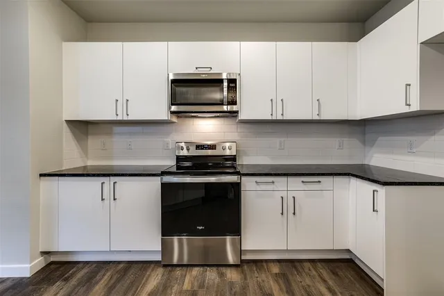 a kitchen with stainless steel appliances granite countertop a stove a microwave and a white cabinets