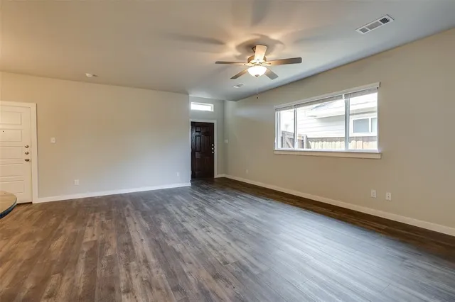 a view of an empty room with wooden floor and a window