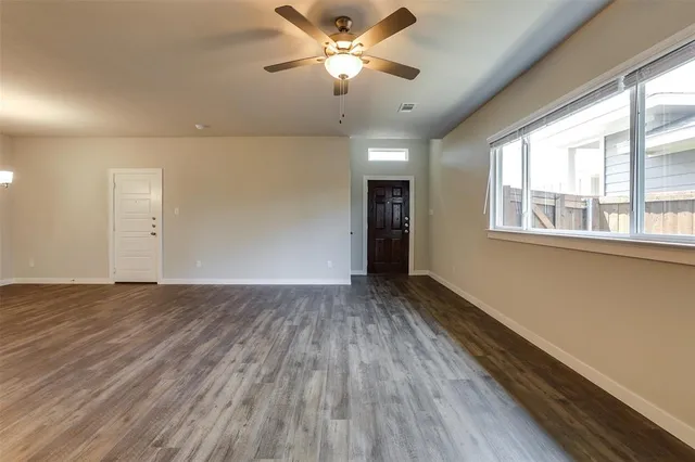 a view of an empty room with a window and wooden floor