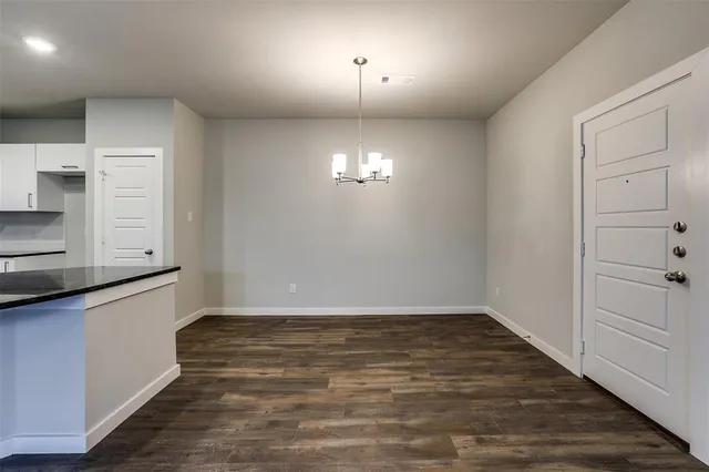 an empty room with wooden floor cabinet and windows