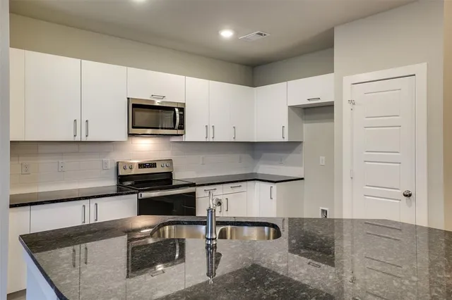 a kitchen with stainless steel appliances granite countertop a stove a sink and a microwave