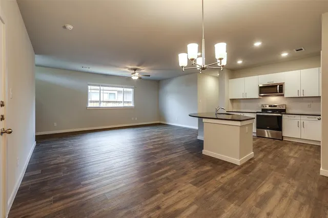 a kitchen with stainless steel appliances a kitchen island hardwood floor and a sink