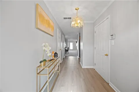 a view of a hallway with wooden floor and chandelier