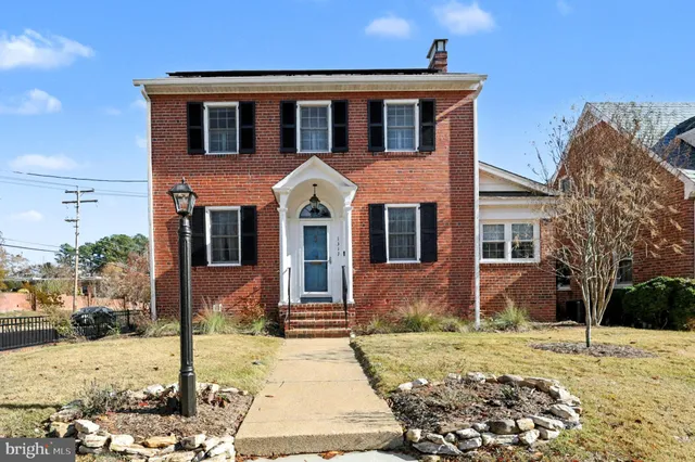 an empty room with wooden floor fireplace and windows