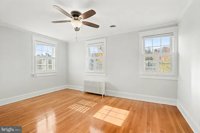 a view of empty room with wooden floor and fan
