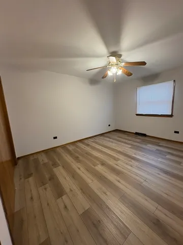 a view of a room with a ceiling fan and wooden floor