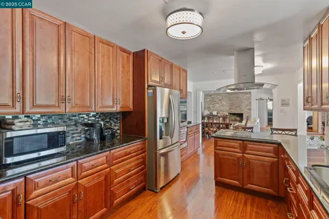 a kitchen with stainless steel appliances granite countertop a stove a sink dishwasher and cabinets with wooden floor