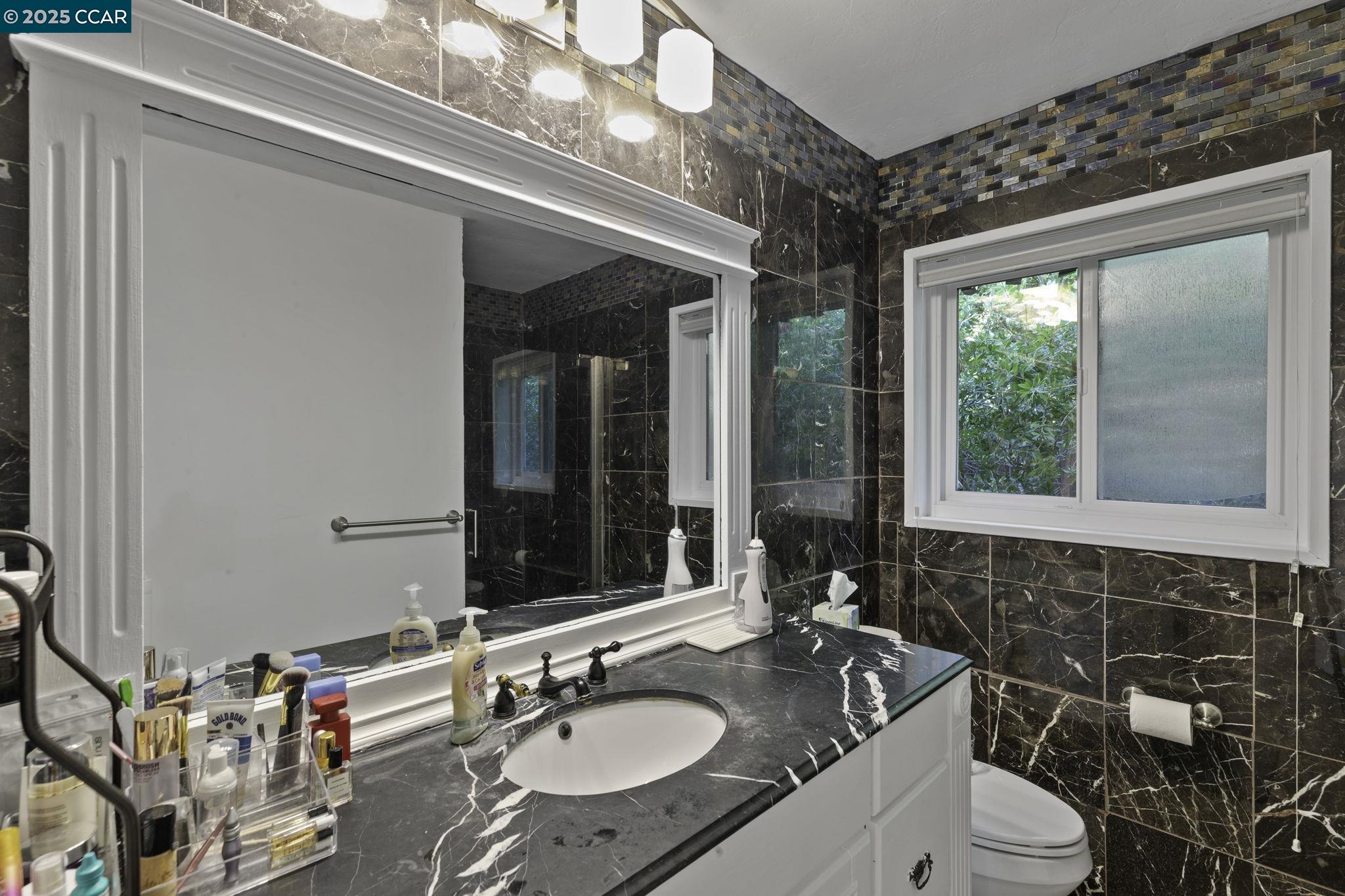 1910 San Miguel Drive Walnut Creek, CA 94596 - Photo 27 of 58 a bathroom with a granite countertop sink and a large mirror