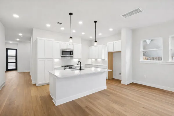 a large kitchen with stainless steel appliances kitchen island a large counter top and a wooden floors