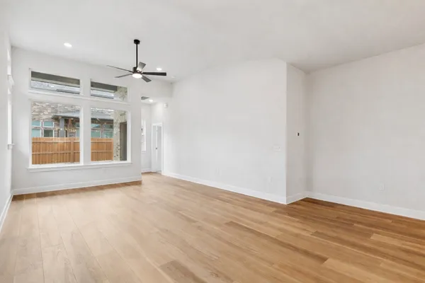 a view of an empty room with wooden floor staircase and a ceiling fan