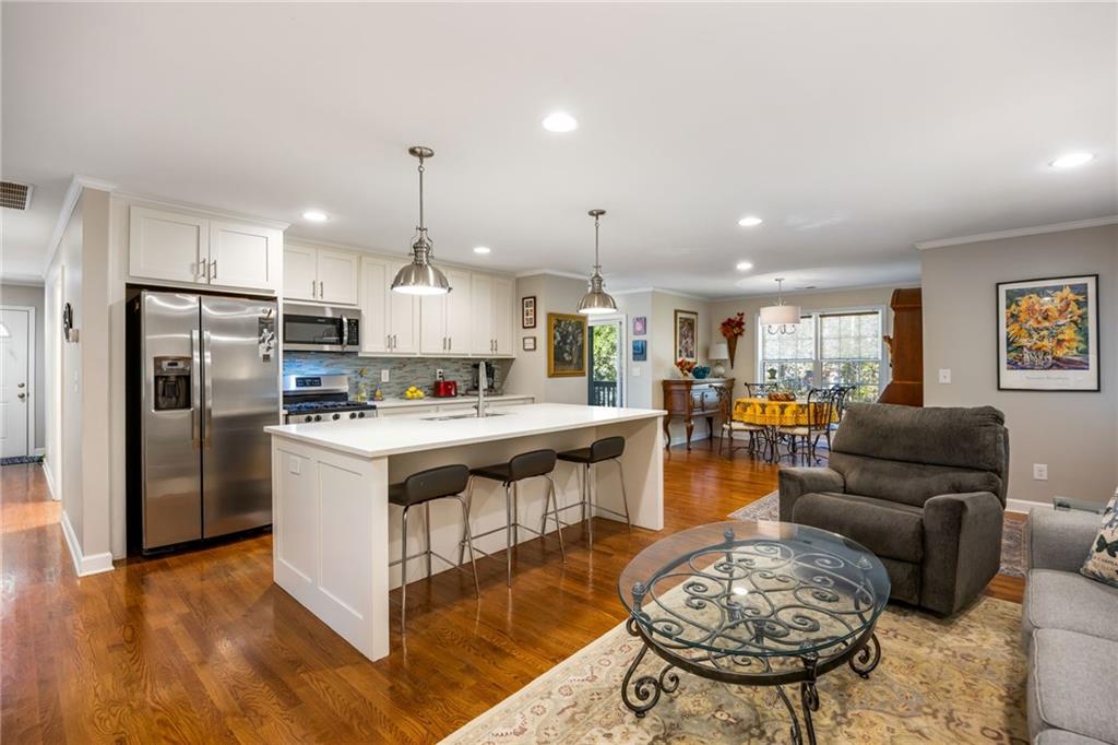 1505 Old John Ward Road Marietta, GA 30064 - Photo 30 of 46 a kitchen with stainless steel appliances kitchen island granite countertop a refrigerator a stove a sink dishwasher and a dining table with wooden floor
