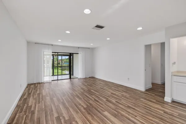 a large white kitchen with kitchen island a sink wooden floor and a refrigerator