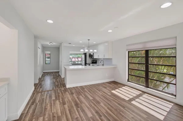 a kitchen with a sink dishwasher and white cabinets with wooden floor
