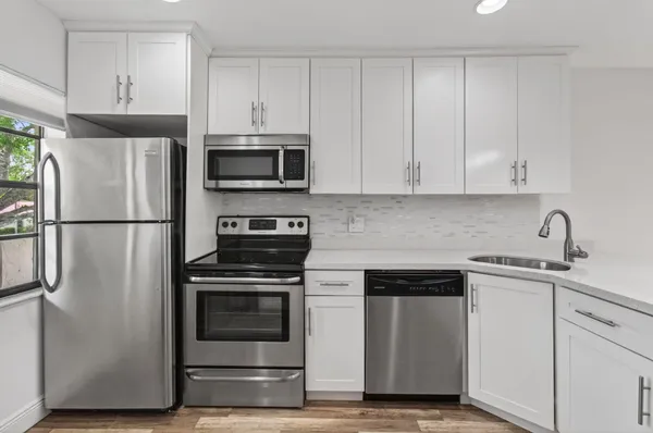 a view of a big room with wooden floor and windows