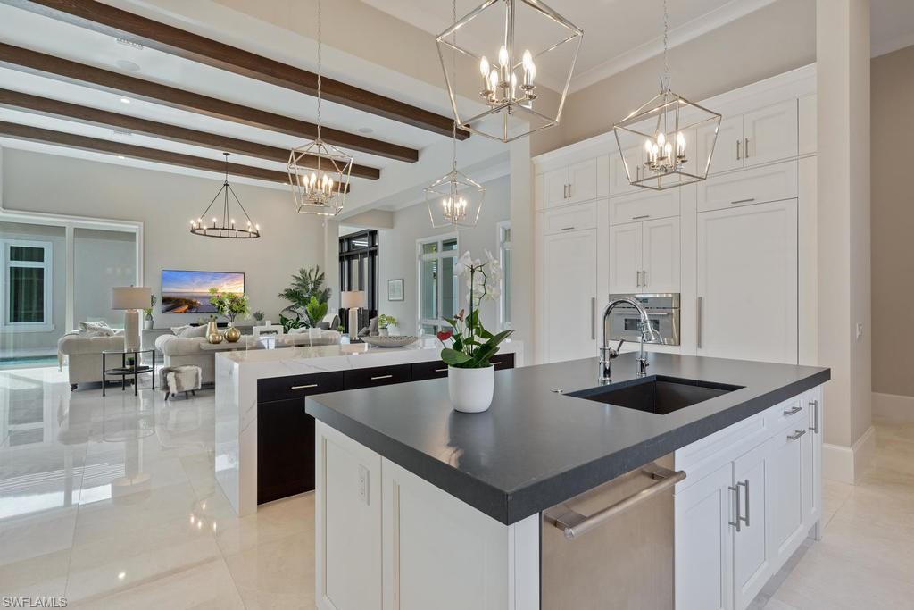4478 Wayside Drive Naples, FL 34119 - Photo 5 of 31 a kitchen with a center island a dining table and chairs