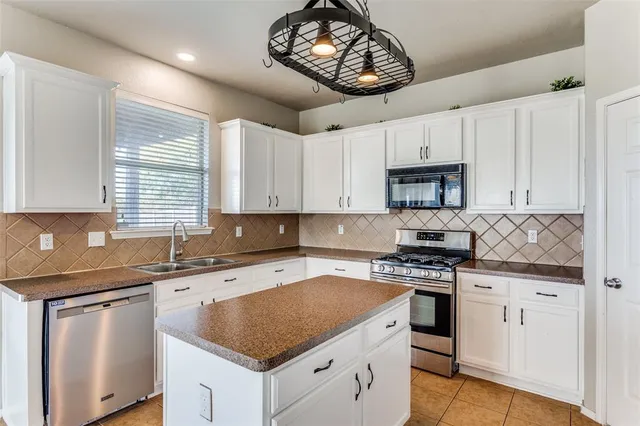 a kitchen with cabinets appliances a sink and a window