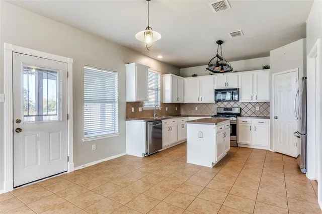 a kitchen with stainless steel appliances granite countertop a refrigerator a sink dishwasher a stove with white cabinets