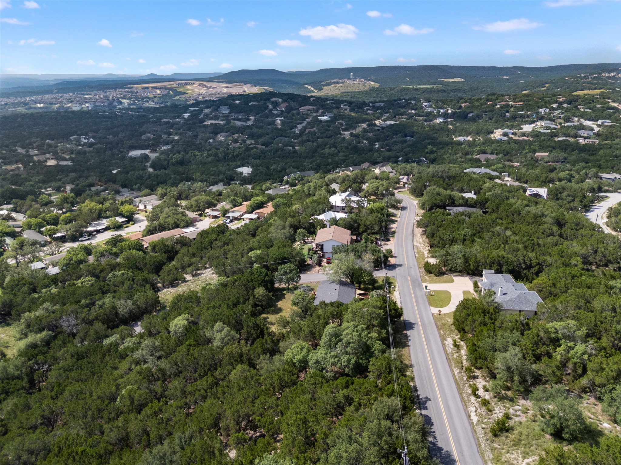 21105 Ridgeview Road Lago Vista, TX 78645 - Photo 15 of 34 An aerial perspective reveals a tree-filled neighborhood nestled against distant hills and a clear blue sky.