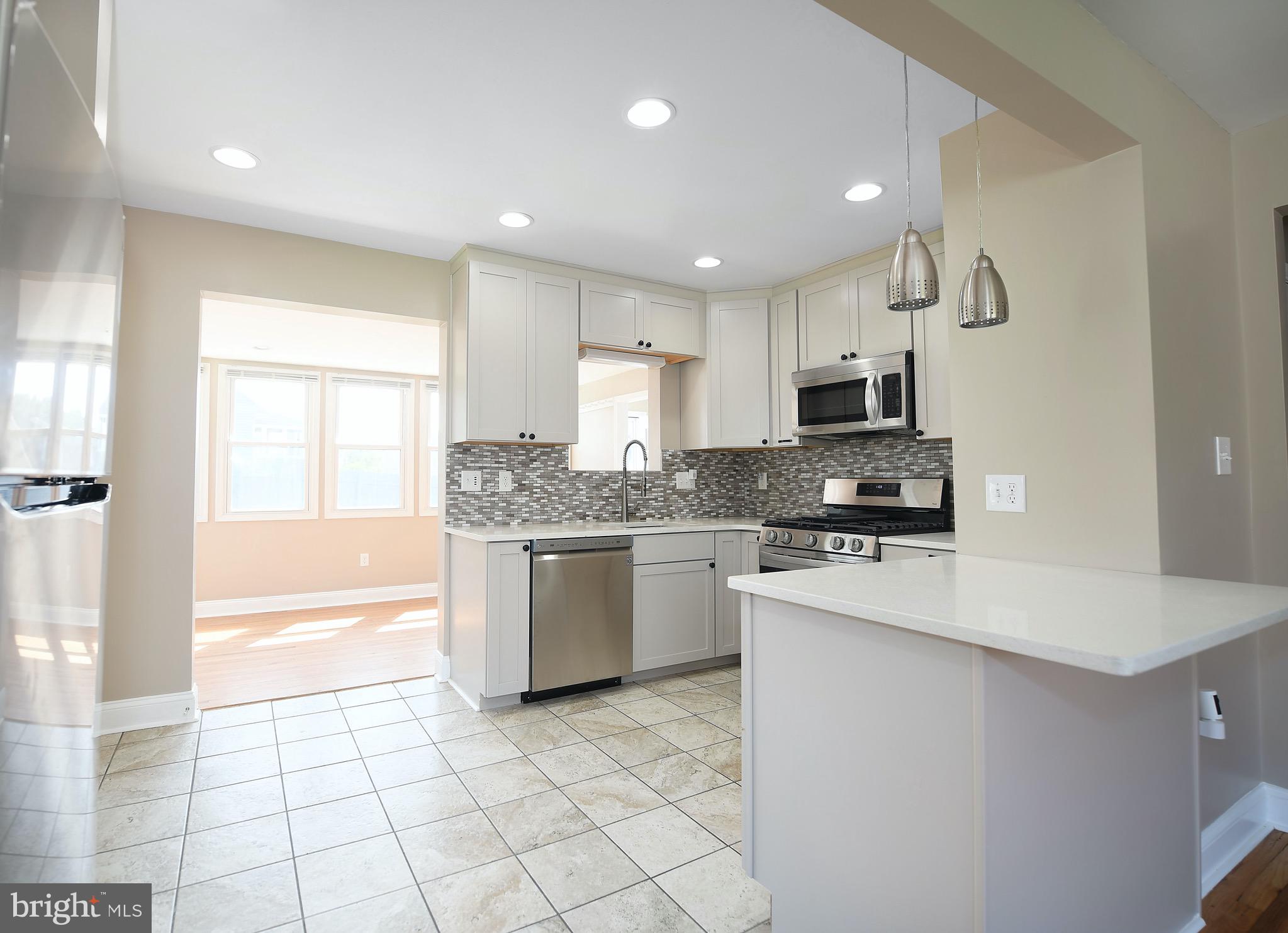 8205 Oakleigh Road Baltimore, MD 21234 - Photo 11 of 52 a kitchen with a sink a stove a microwave a counter top space and cabinets