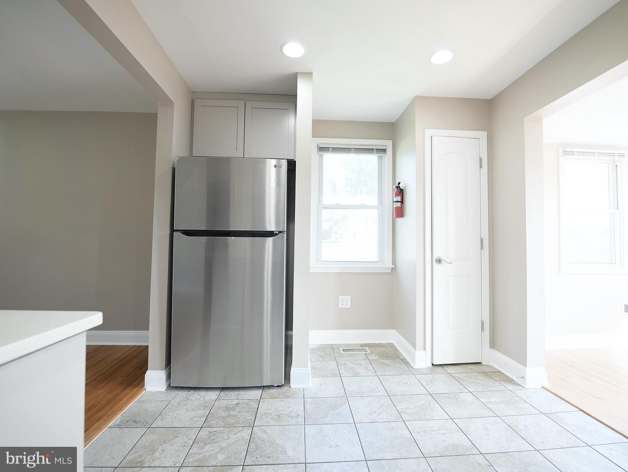 8205 Oakleigh Road Baltimore, MD 21234 - Photo 13 of 52 a view of a refrigerator in kitchen and an empty room in wooden floor