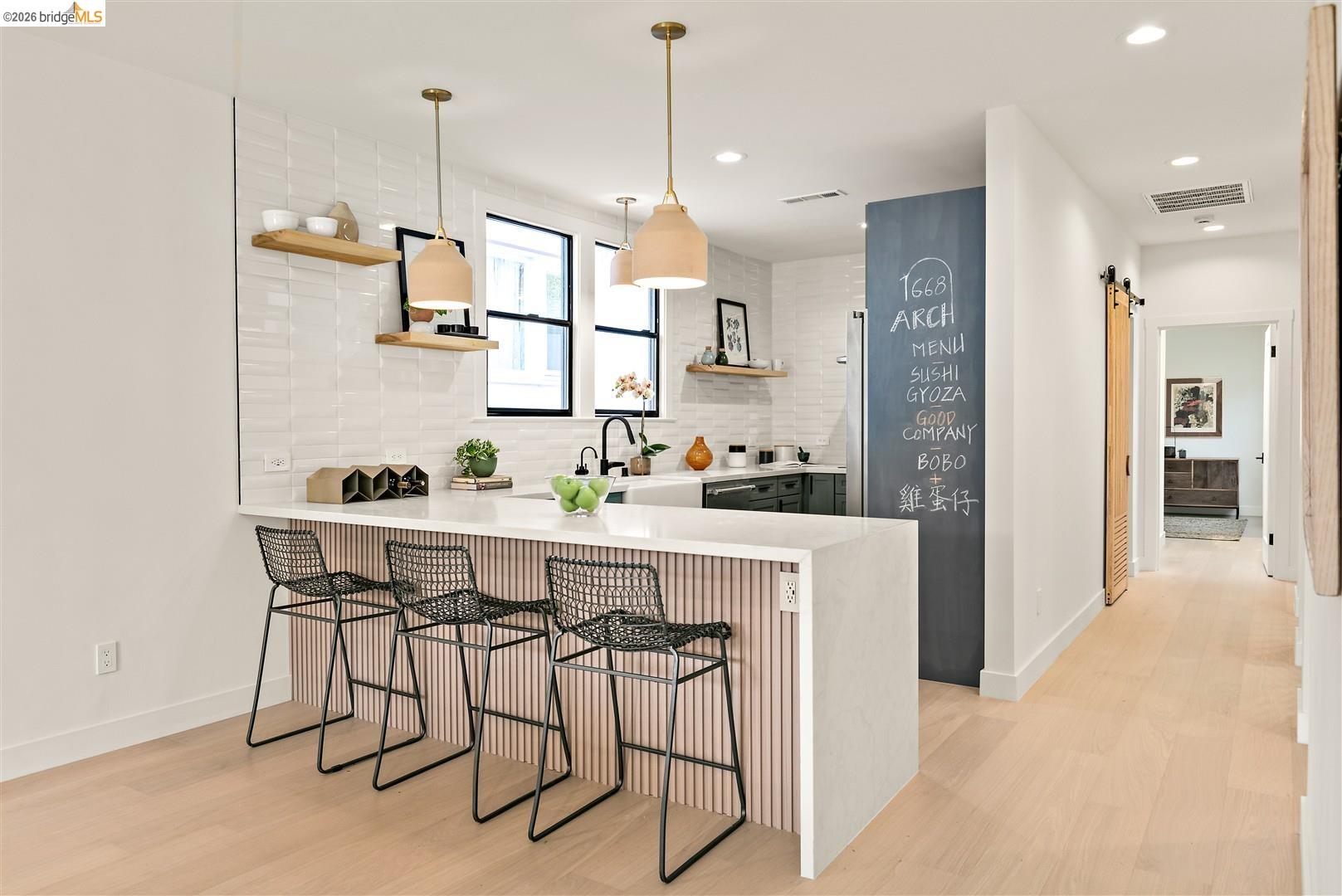 1668 Arch Street Berkeley, CA 94709 - Photo 18 of 78 Modern kitchen island with a light-toned wood-finish base and light-toned countertop, complemented by two pendant lights and recessed lighting