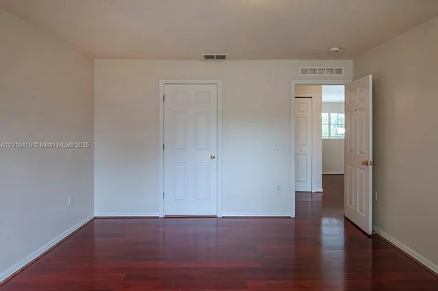 a view of an empty room with wooden floor and closet