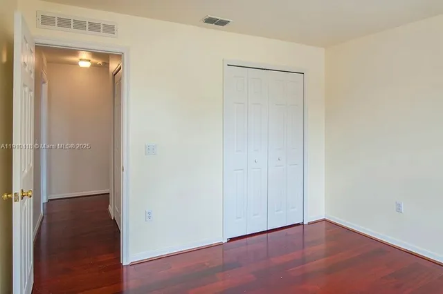 a view of an empty room with closet and a bathroom