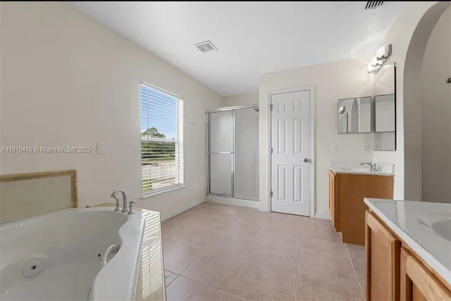 a spacious bathroom with a tub sink and mirror