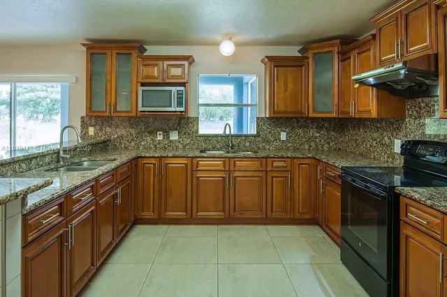 a kitchen with stainless steel appliances granite countertop a sink stove and cabinets