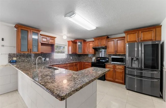 a kitchen with stainless steel appliances granite countertop a sink stove and refrigerator